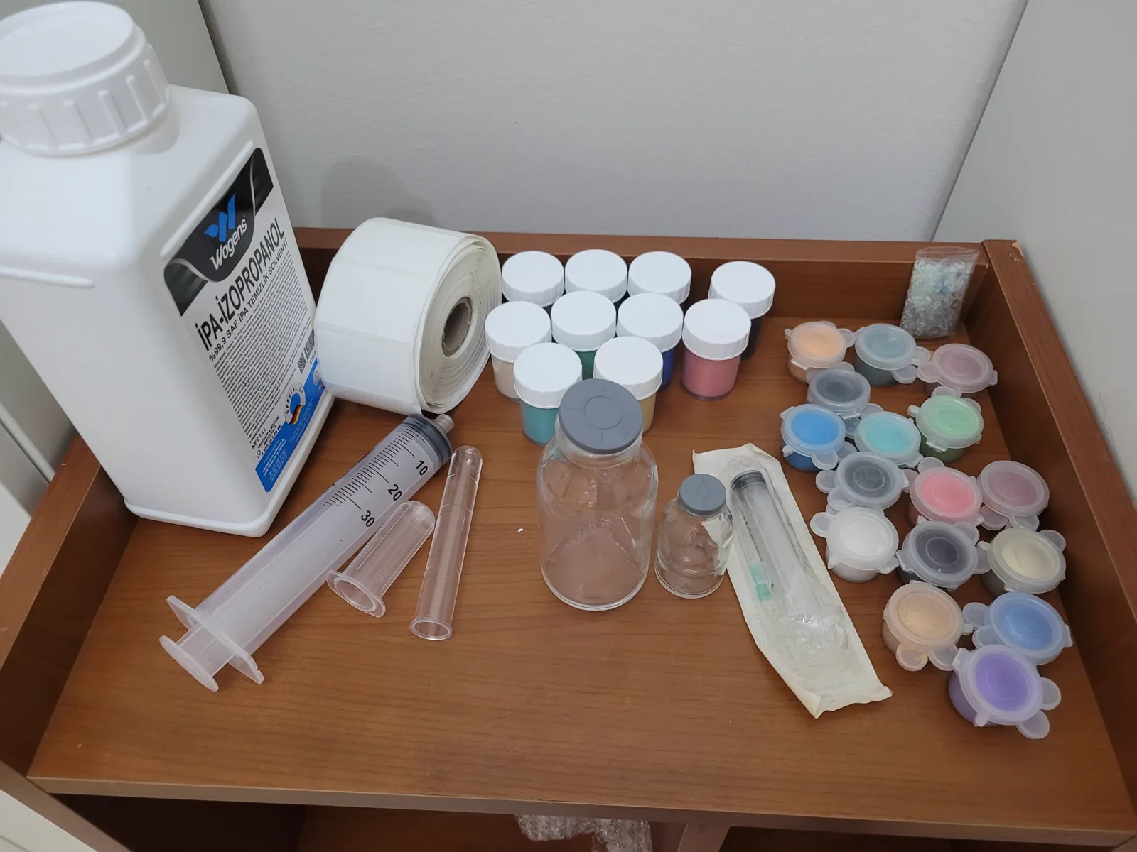 Atölye masasında iksir malzemeleri: gliserin, pigment ve mika tozu kapları, boş şişeler, ölçü şırıngaları